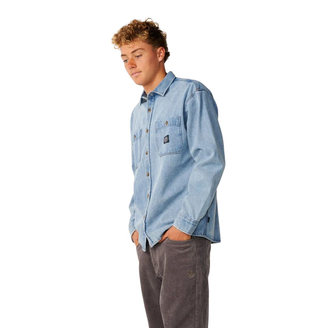 Vista de perfil de la camisa vaquera Rip Curl Premium Surf Denim L/S en Washed Blue, mostrando el cuello camisero, los bolsillos de parche y la caída holgada de la prenda.