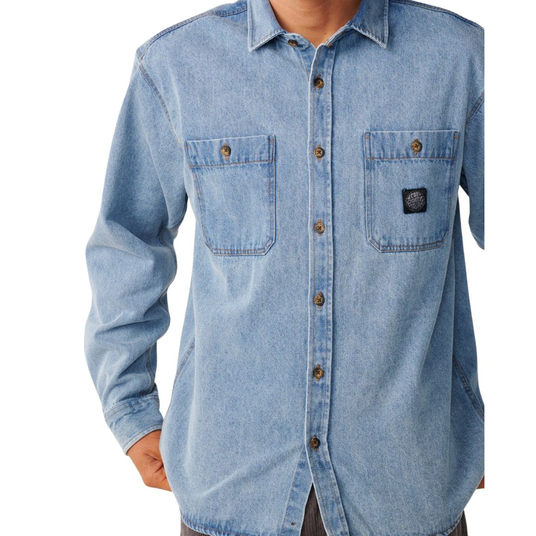 Detalle de los dos bolsillos de parche en el pecho de la camisa vaquera Rip Curl Premium Surf Denim L/S en Washed Blue, con el parche tejido circular Rip Curl y botones de resina.