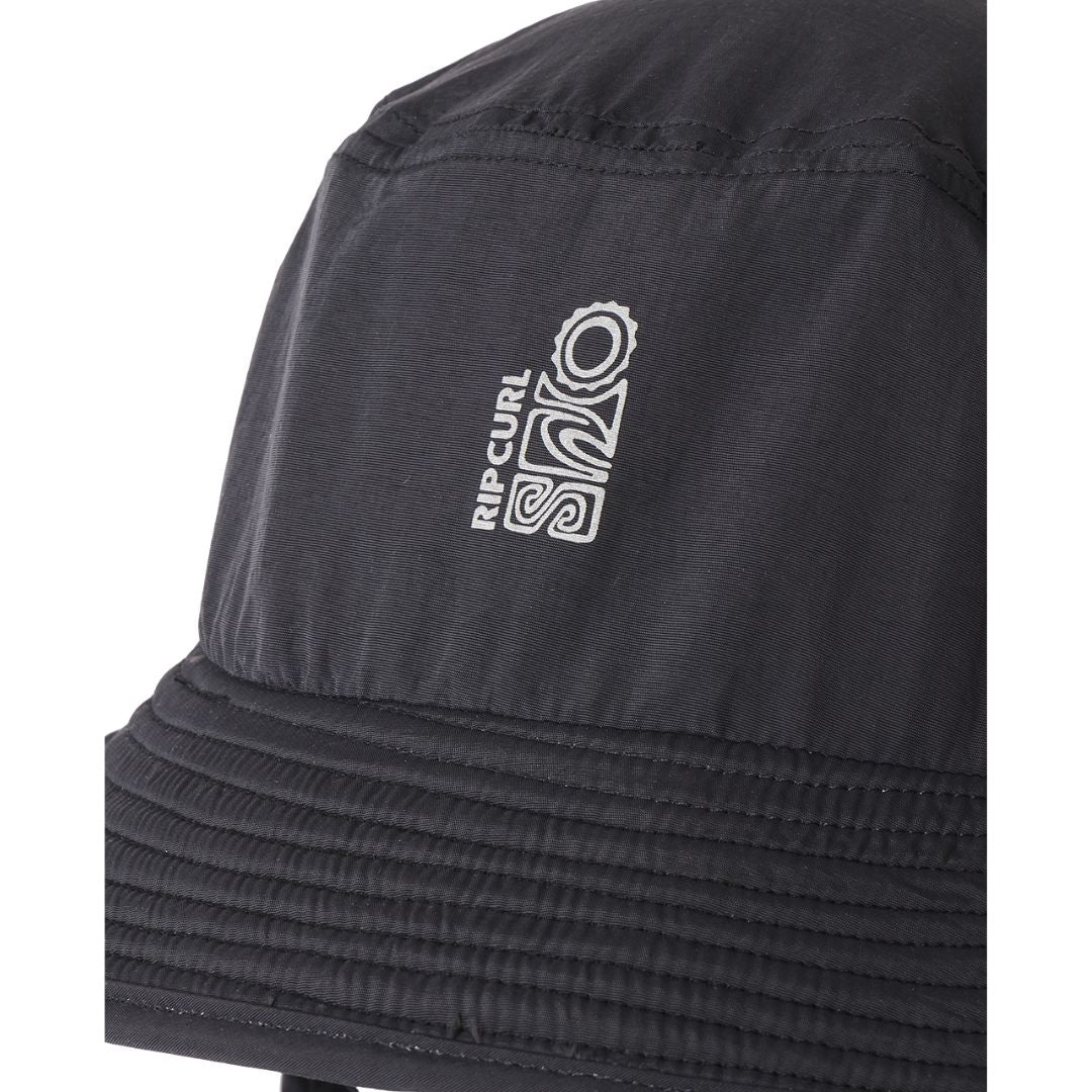 Detalle del ala flotante Bloom™ y logo Rip Curl S-Series bordado en tono gris sobre tela de poliamida negra, costura de ala reforzada en primer plano.