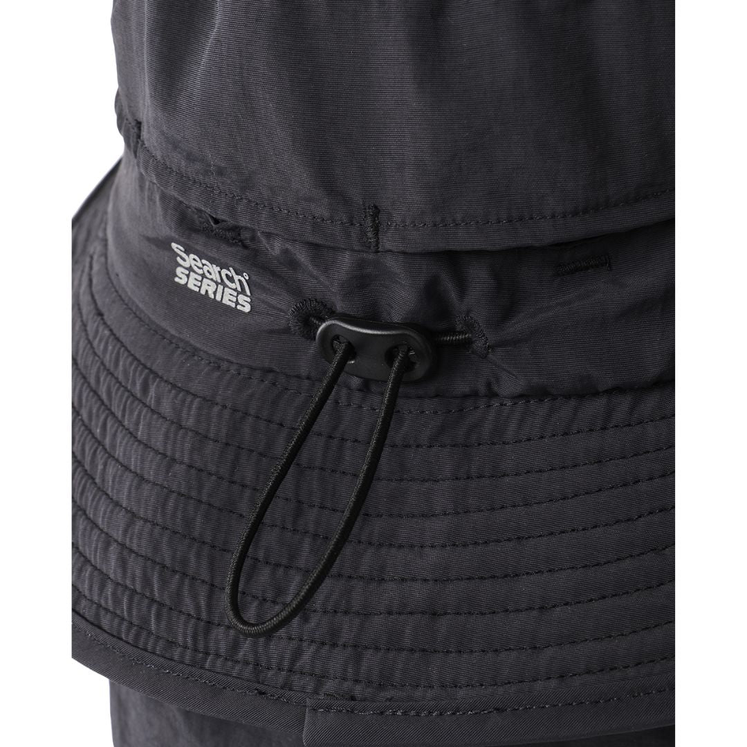 Detalle del cordón ajustador y cierre de presión en la unión copa-ala del Rip Curl S-Series Surf Hat negro, con etiqueta Search Series en primer plano.