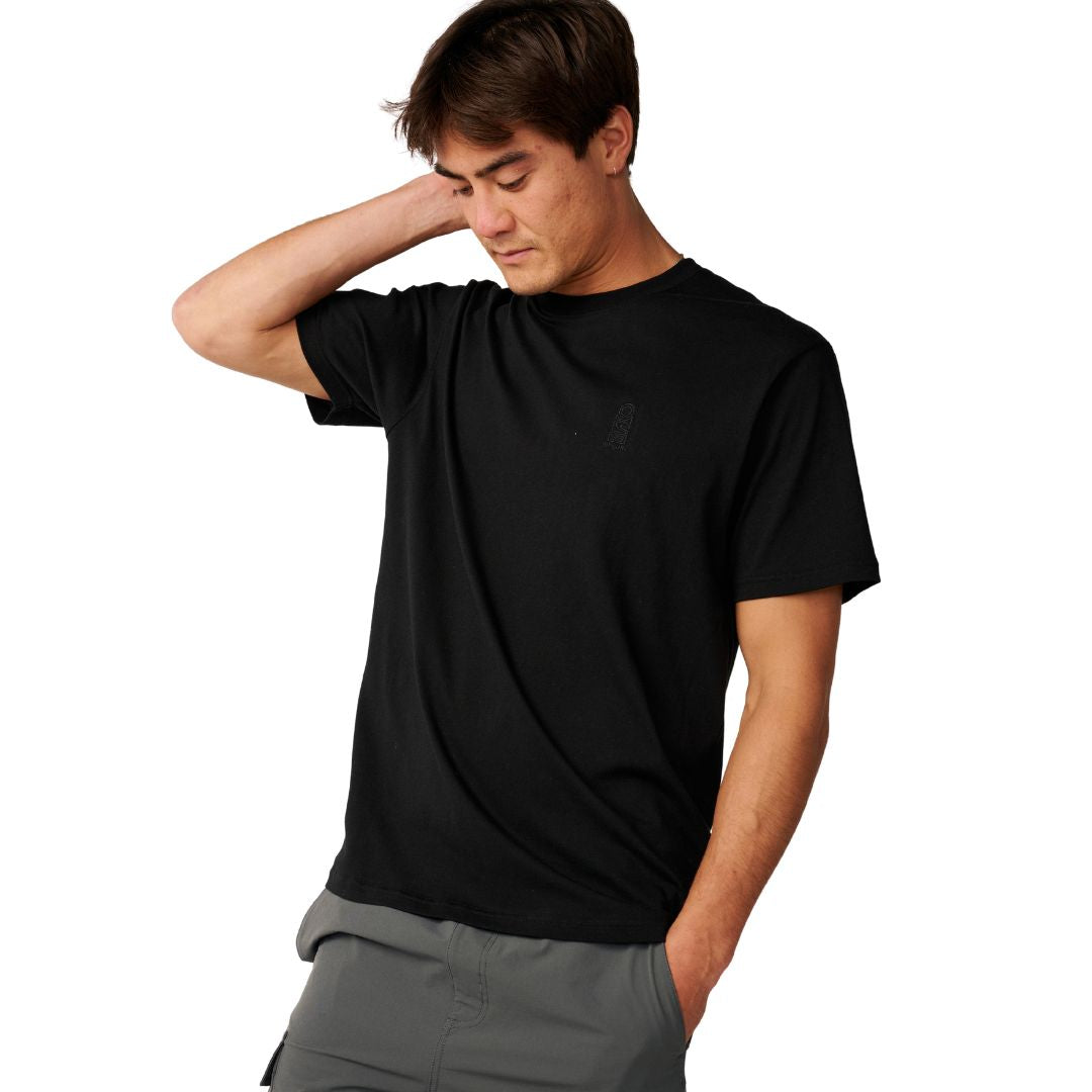 Rip Curl S-Series VaporCool Embroid Tee en color negro, vista frontal recortada con el modelo llevándose la mano a la cabeza, logo bordado tono sobre tono en el pecho.