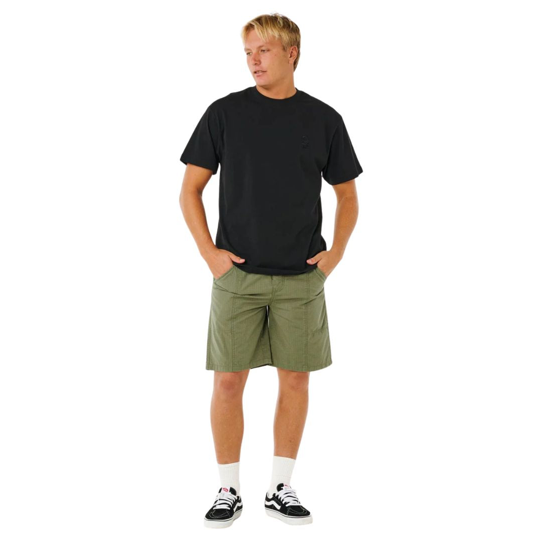 Bañador surf largo Rip Curl Search Destroy Volley 21 verde cactus, vista frontal completa con camiseta negra, relaxed fit por debajo de la rodilla.