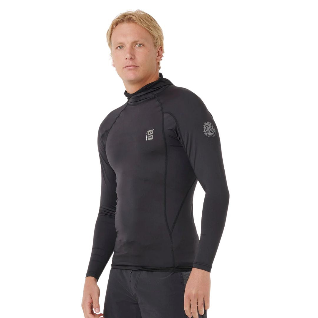 Vista de tres cuartos de un hombre vistiendo la licra técnica Rip Curl Search UPF Performance Hood de manga larga en color negro, destacando el ajuste de alto rendimiento.
