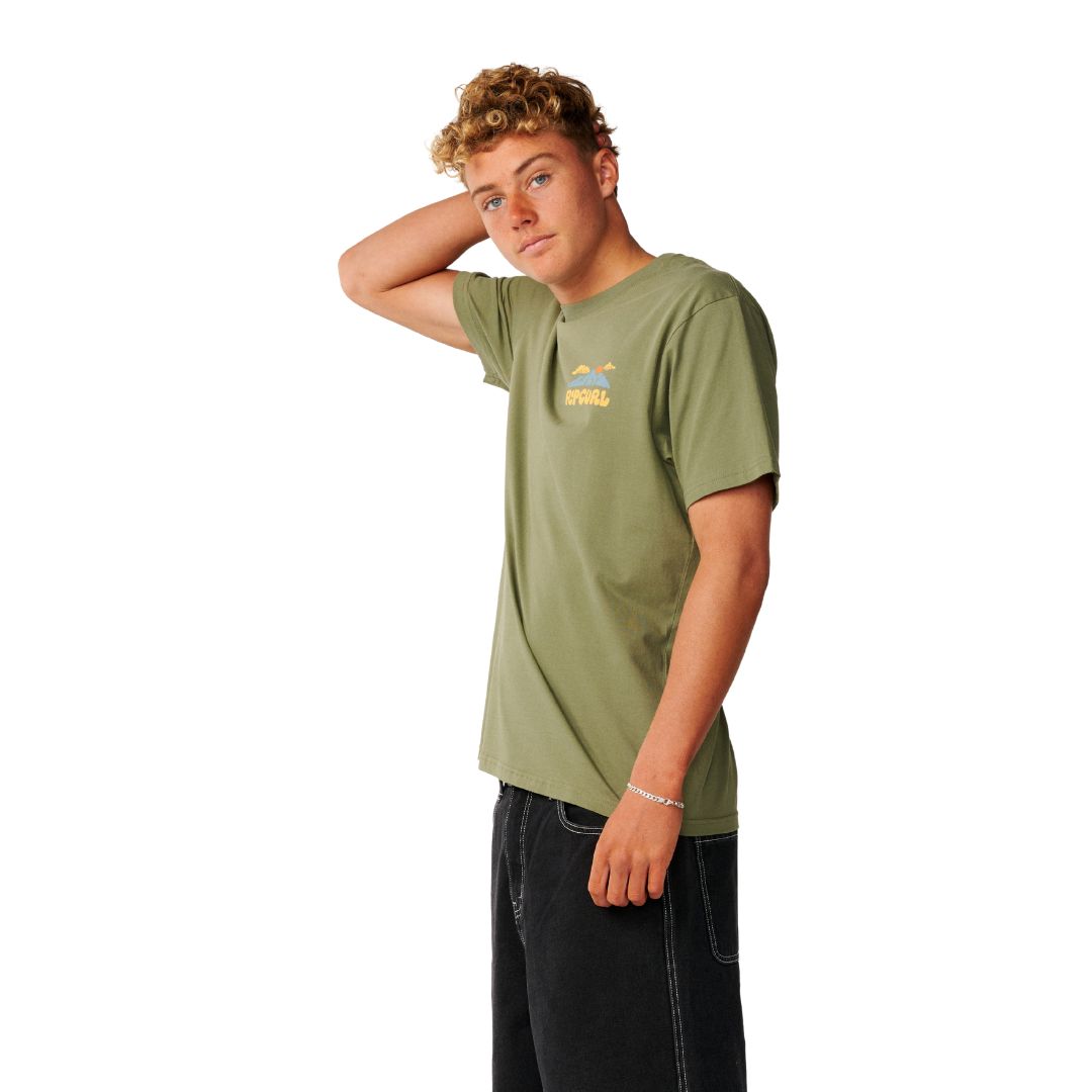 Rip Curl Surf Trip Tee en Surplus Green, vista lateral de tres cuartos, mostrando el logo de montaña estampado en el pecho.