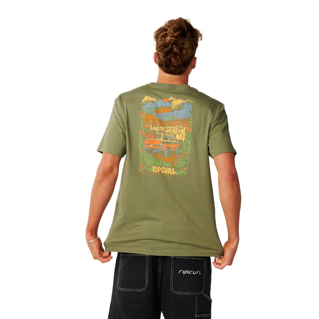 Camiseta Rip Curl Surf Trip Tee en Surplus Green, vista trasera con la ilustración "Live The Search" y una furgoneta naranja cargada de tablas.