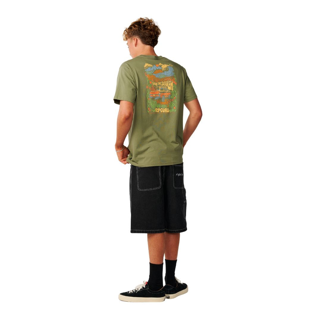 Rip Curl Surf Trip Tee en Surplus Green combinada con bermuda negra, vista trasera de cuerpo entero mostrando el estampado completo.