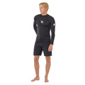 Vista completa del conjunto con licra Rip Curl Waves UPF Perf L/S negra, modelo masculino de pie en postura relajada.