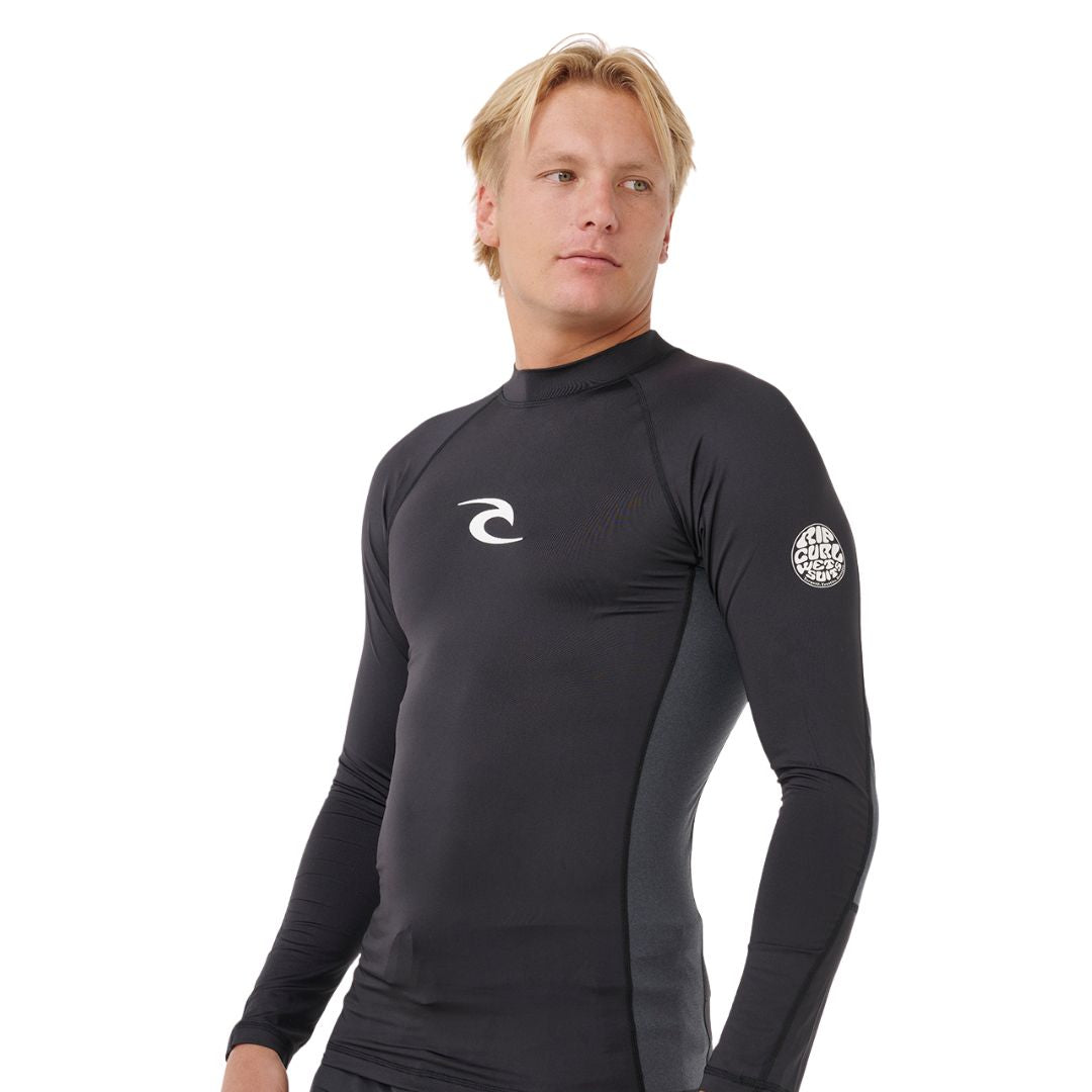 Licra de surf Rip Curl Waves UPF Perf L/S negra, vista frontal media con logo en el pecho y modelo masculino.