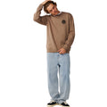 Modelo con sudadera Rip Curl Wetsuit Icon Crew Walnut combinada con vaqueros claros y zapatillas deportivas.