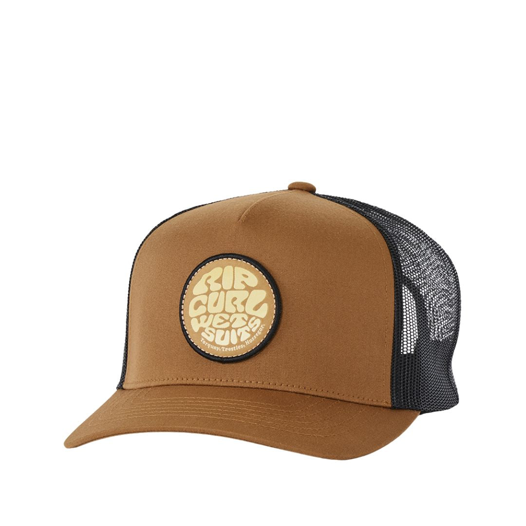 Gorra trucker Rip Curl Wetsuits en color mostaza, vista frontal en ángulo con el parche circular bordado del logo Rip Curl Wetsuits Torquay Trestles Hossegor y la malla trasera negra transpirable.