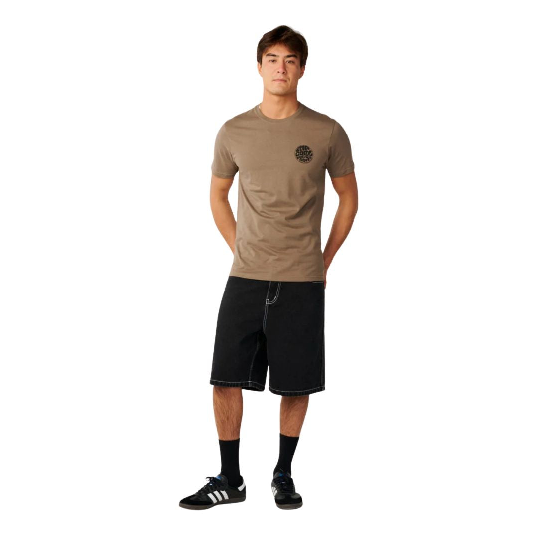 Modelo con camiseta Rip Curl Wettie Icon Walnut combinada con pantalón corto negro y zapatillas deportivas.