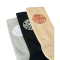 Detalle del puño y logo circular Rip Curl Wetsuits tejido en los tres calcetines Wetty Crew Sock, en blanco sobre gris y negro, y en terracota sobre beige.