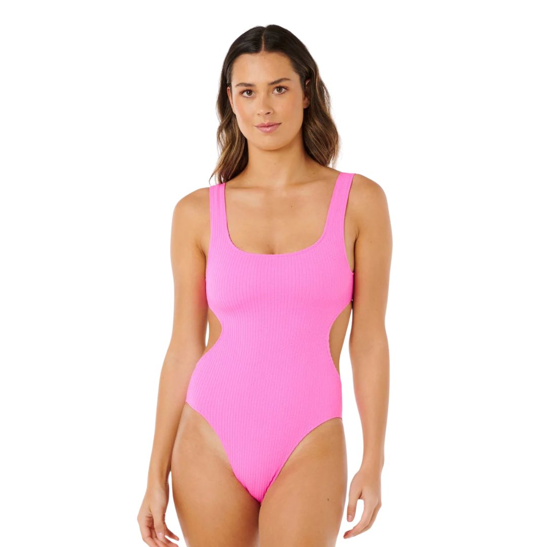 Bañador entero colaboración Rip Curl x Surf City 1PC rosa super pink, vista frontal con cut-out bilateral simétrico y tejido tubular acanalado elástico.