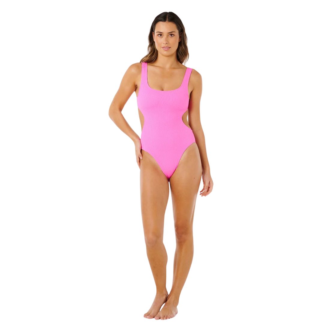 Mujer con bañador entero Rip Curl x Surf City 1PC rosa super pink, vista frontal completa con cut-out lateral bilateral y tejido tubular acanalado.