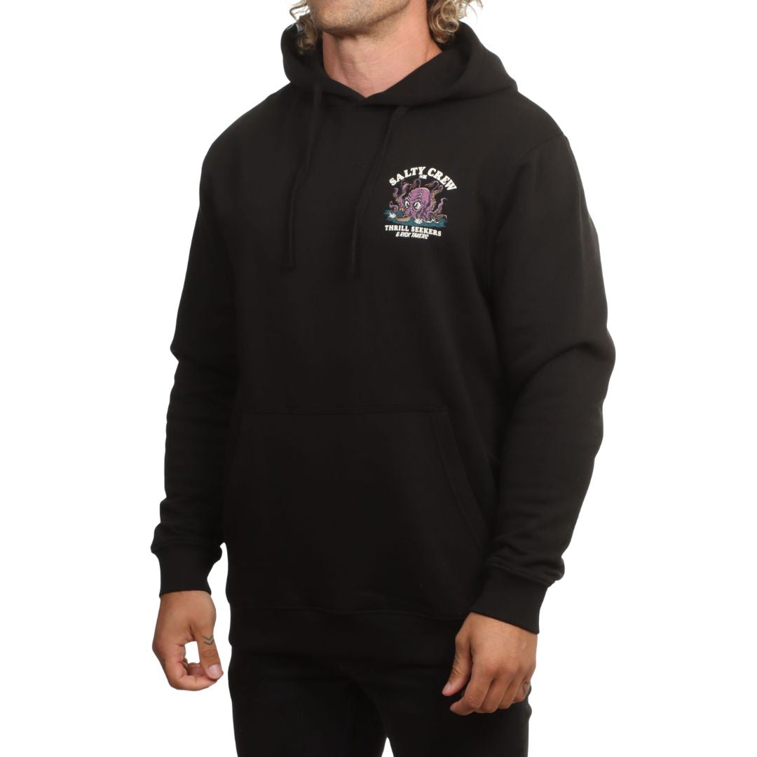 Modelo con la sudadera Salty Crew Kraken Monster en negro, capucha con cordón ajustable, manos en el bolsillo canguro y el gráfico del kraken serigrafiado en el pecho.