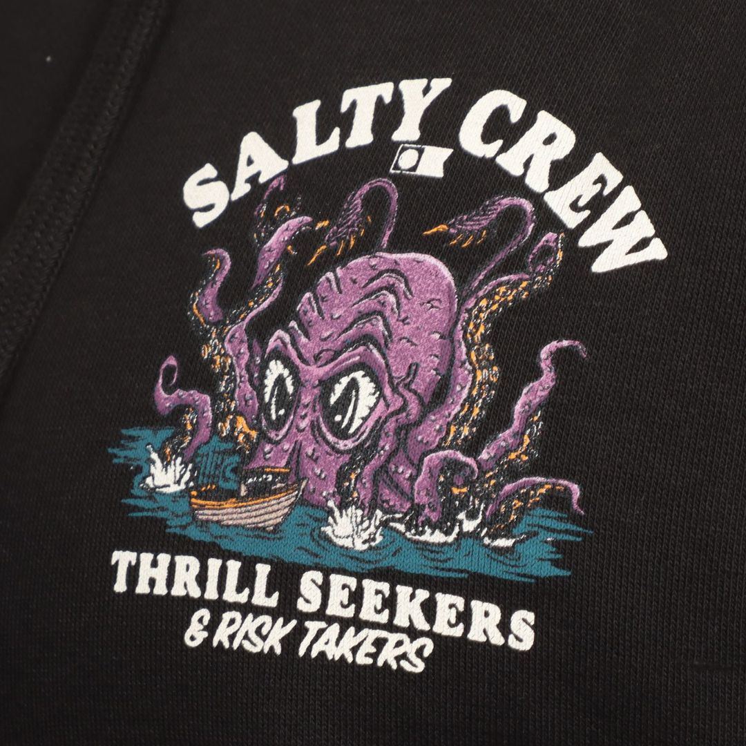 Primer plano del estampado de la sudadera Salty Crew Kraken Monster en negro, con el monstruo morado atacando un barco y los textos Salty Crew y Thrill Seekers & Risk Takers.