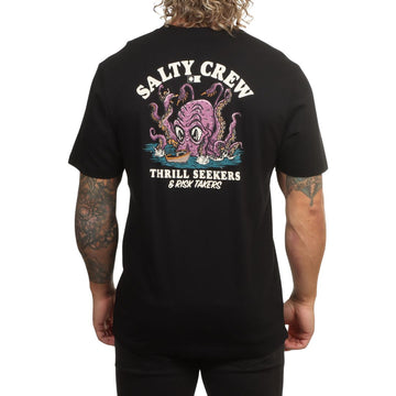 Modelo visto de espaldas con la camiseta Salty Crew Kraken Monster en negro, luciendo el estampado completo del kraken atacando un barco y el texto Thrill Seekers & Risk Takers.