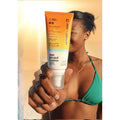 Mujer sosteniendo Seventy One Percent Sun Kissed Lotion SPF50+ White, protector solar SPF50+ de rápida absorción para cara y cuerpo.