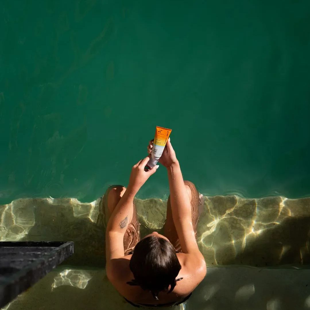 Aplicación de protector solar Seventy One Percent Sun Kissed Lotion SPF50+ White en piscina, loción invisible resistente al agua para uso outdoor.