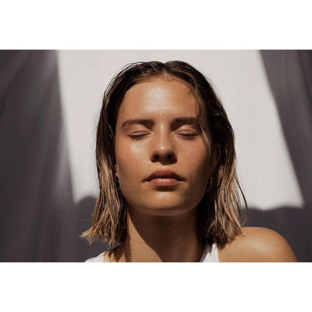 Mujer con piel protegida al sol usando protector solar invisible SPF50 rostro acabado natural.