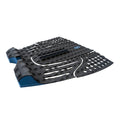 Grip de surf trasero Slater Designs 5 Piece Action Pad negro y azul en perspectiva, mostrando arco bajo con ranuras paralelas, kick tail azul con corte en V, textura de diamante BLOOM y adhesivo 3M.
