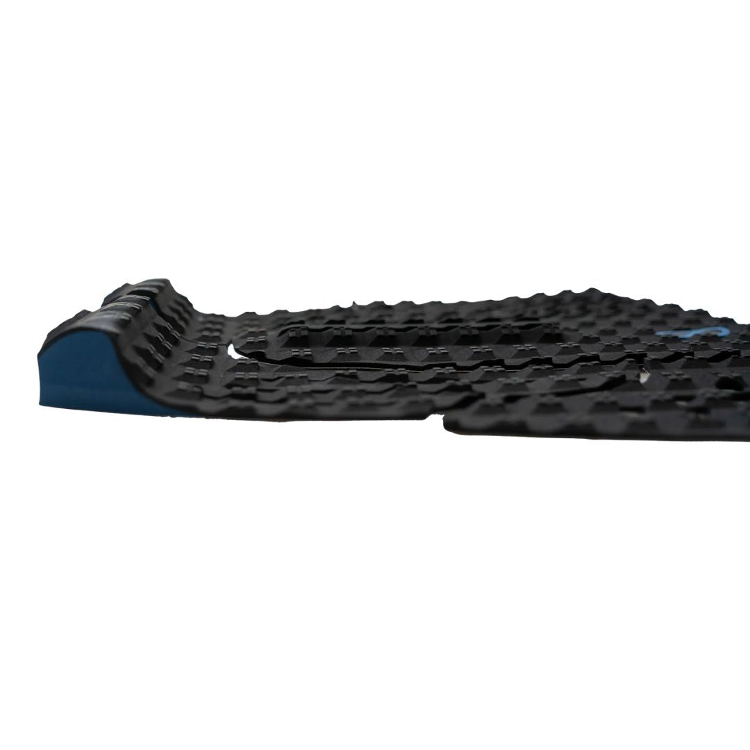 Vista lateral del grip Slater Designs 5 Piece Action Pad negro y azul, perfil del kick tail azul con corte en V anti-enganche de invento y textura de diamante espuma BLOOM de algas visible.