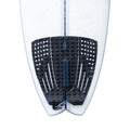 Grip Slater Designs 5 Piece Action Pad negro y azul instalado en tabla de surf Firewire blanca, vista cenital de la cola mostrando las 5 piezas, arco bajo azul, ranuras paralelas y recortes circulares.