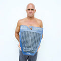 Kelly Slater sosteniendo el embalaje original del Slater Designs Action Pad 5 Piece Algae Foam con logo BLOOM azul, mostrando especificaciones 5mm grosor, arco 8mm y kick 27mm.