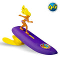 Surfer Dudes Classics Series 2 Newport Naomi, mini surfista boomerang de playa en color morado, con melena amarilla y bikini a juego, sobre tabla insumergible con quilla amarilla.