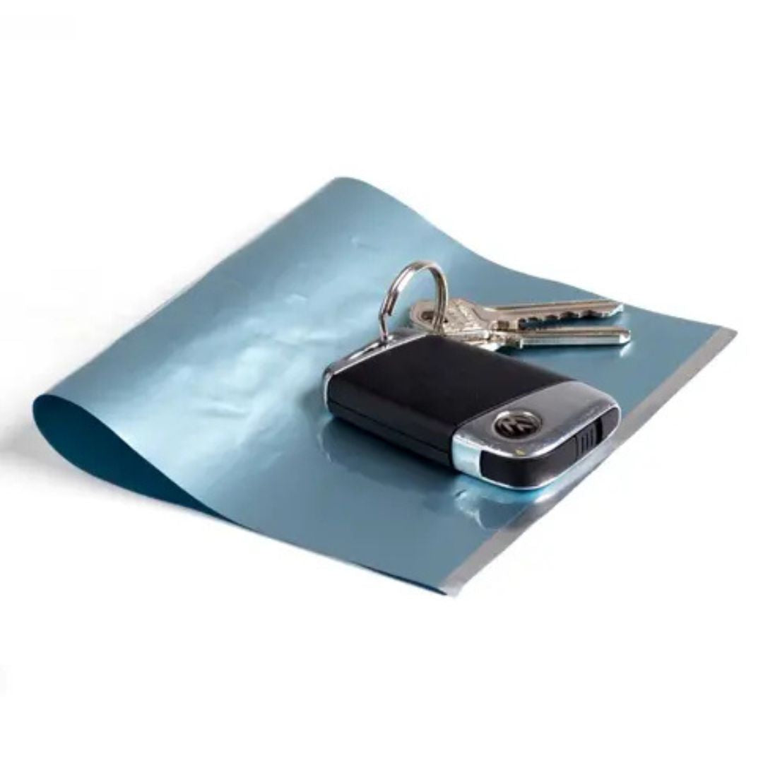 Bolsa bloqueadora de señal incluida con el candado guarda llaves Surflogic, extendida sobre fondo blanco junto a un juego de llaves de coche con mando de proximidad.