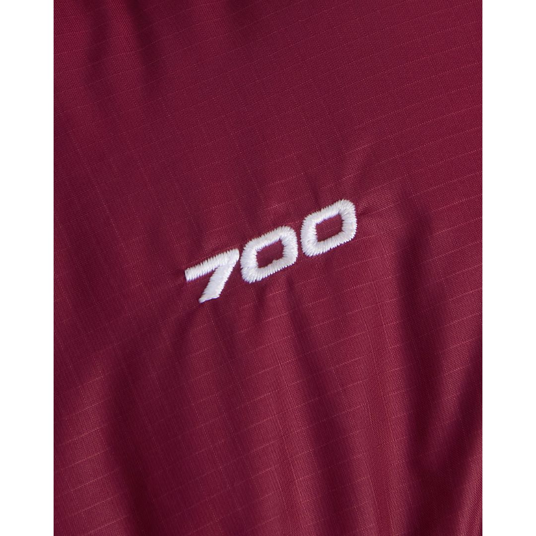 Detalle del número 700 bordado en blanco sobre el tejido ripstop granate de la chaqueta de plumas The North Face Nuptse, que indica el poder de relleno del plumón.