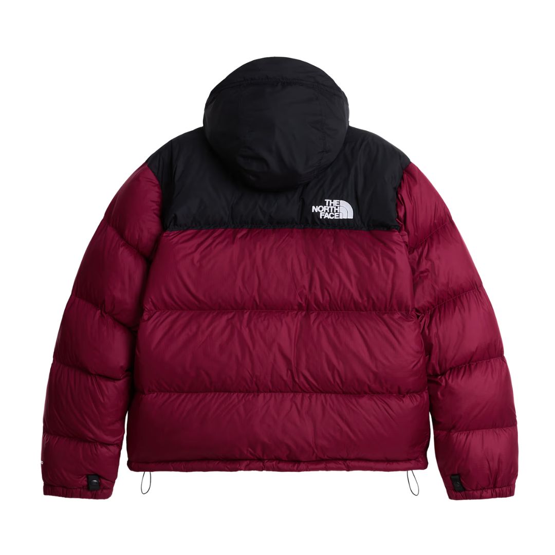 Vista trasera de la chaqueta de plumas The North Face Nuptse en granate con canesú y capucha negros, logo bordado en la espalda, cordones del bajo y gomas en los puños.