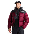 Modelo con la chaqueta de plumas The North Face Nuptse granate y hombros negros, abierta sobre un forro polar estampado, con gorra negra y pantalón técnico oscuro.