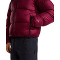 Lateral de la chaqueta de plumas The North Face Nuptse granate con la mano en el bolsillo con cremallera, costuras acolchadas horizontales y la etiqueta 700 en la manga.