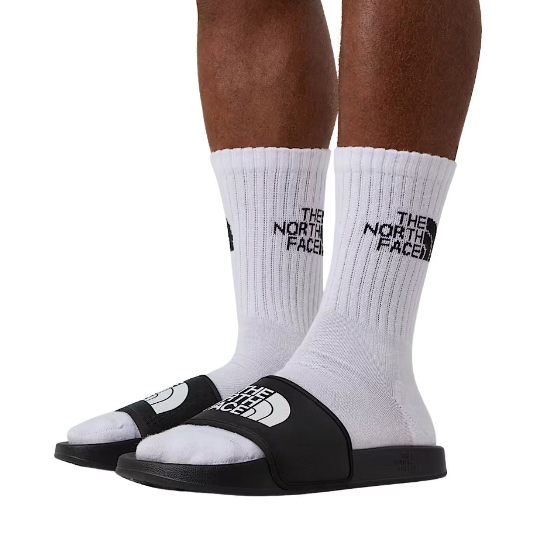 Detalle de las chanclas The North Face Base Camp Slide III negras usadas con calcetines.