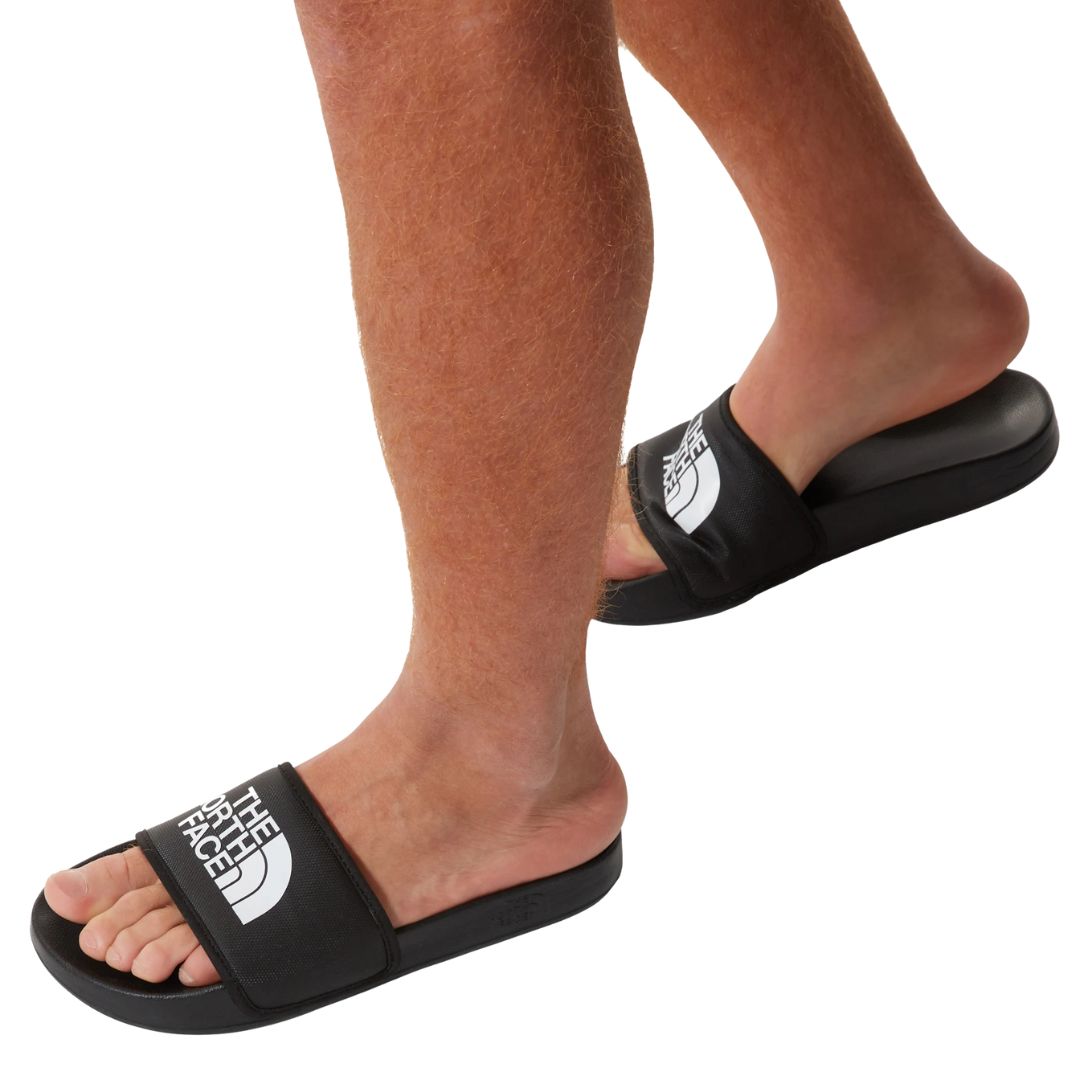 Chanclas The North Face Base Camp Slide III negras con logo blanco, vista en uso caminando sin calcetines.