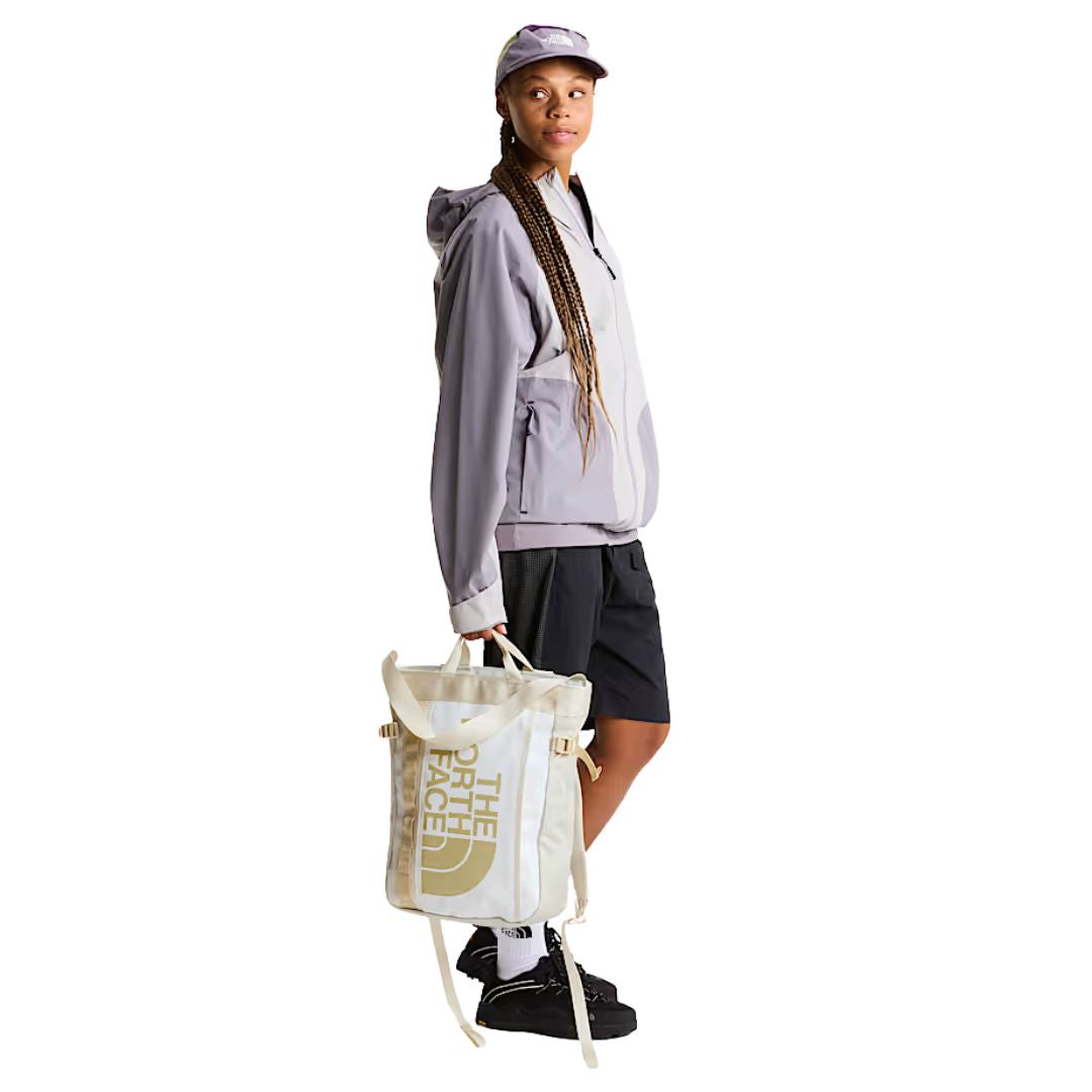 Mochila tote The North Face Base Camp Tote Pack en color White Ash utilizada como bolso de mano, mostrando versatilidad de transporte.
