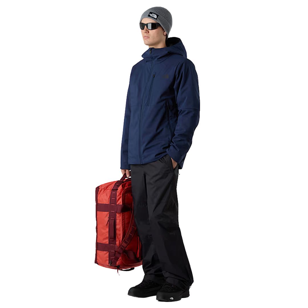 Detalle del compartimento lateral de la bolsa The North Face Base Camp Voyager Duffel 42L con zapatillas deportivas guardadas.