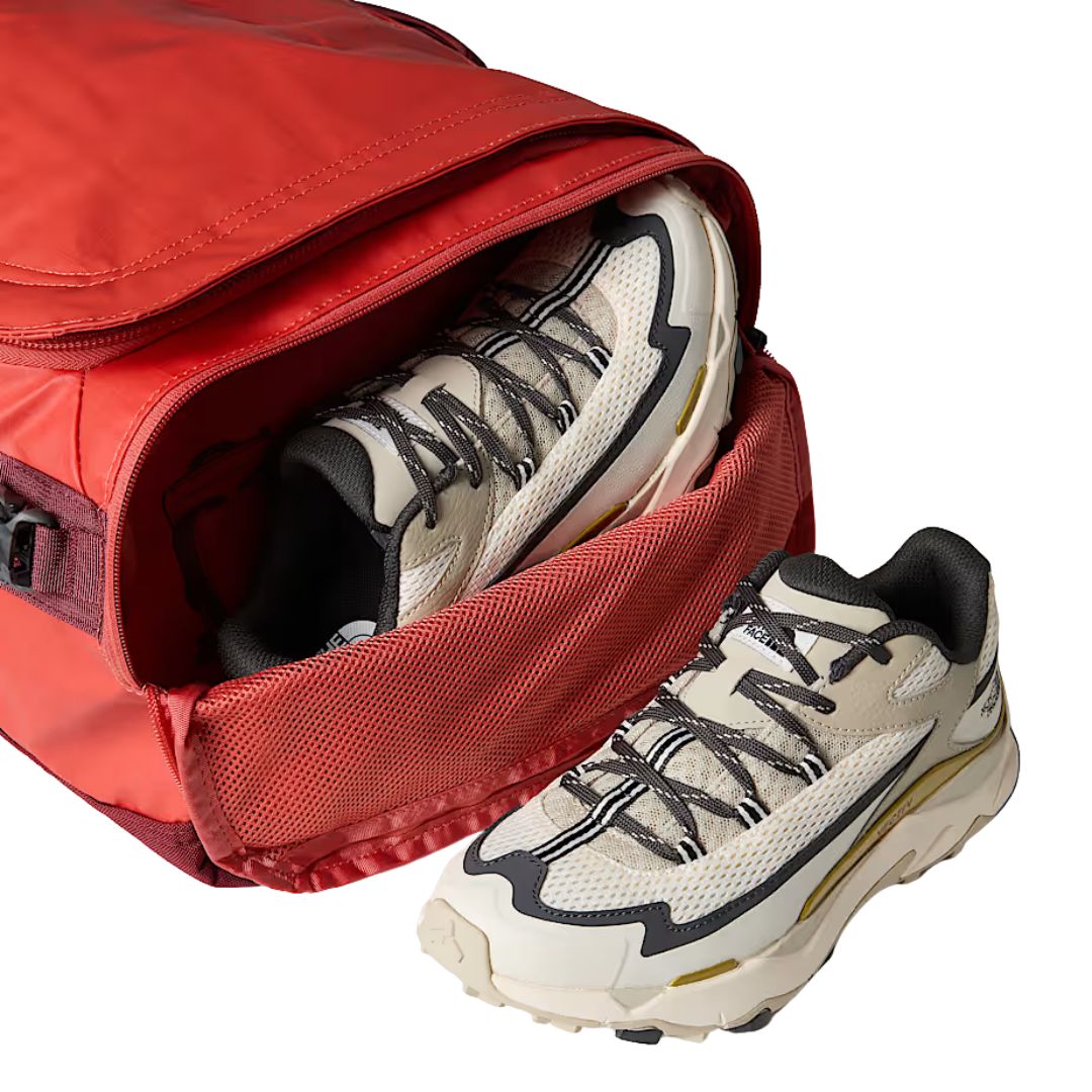 Hombre con gorro gris y chaqueta azul cargando al hombro la bolsa The North Face Base Camp Voyager Duffel 42L color Mars Dust.