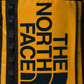 Detalle del logo The North Face en mochila Base Camp Fuse Box color amarillo Summit Gold.