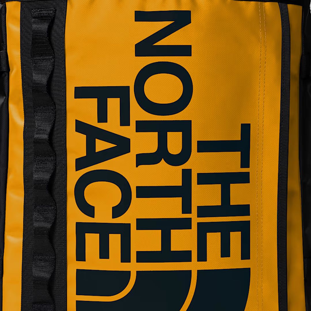 Detalle del logo The North Face en mochila Base Camp Fuse Box color amarillo Summit Gold.