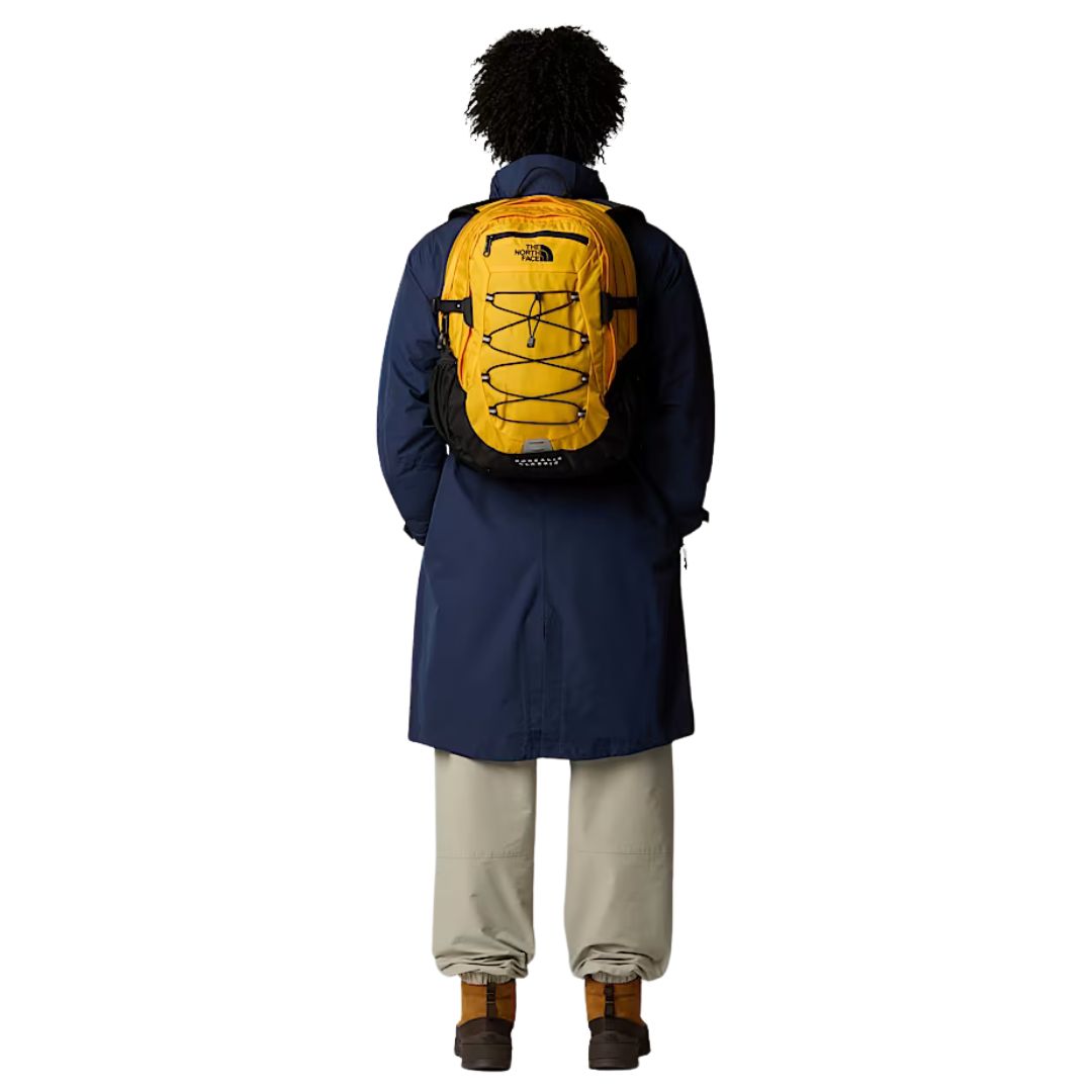 Mochila The North Face Borealis Classic en color Summit Gold vista desde la espalda sobre modelo con abrigo largo