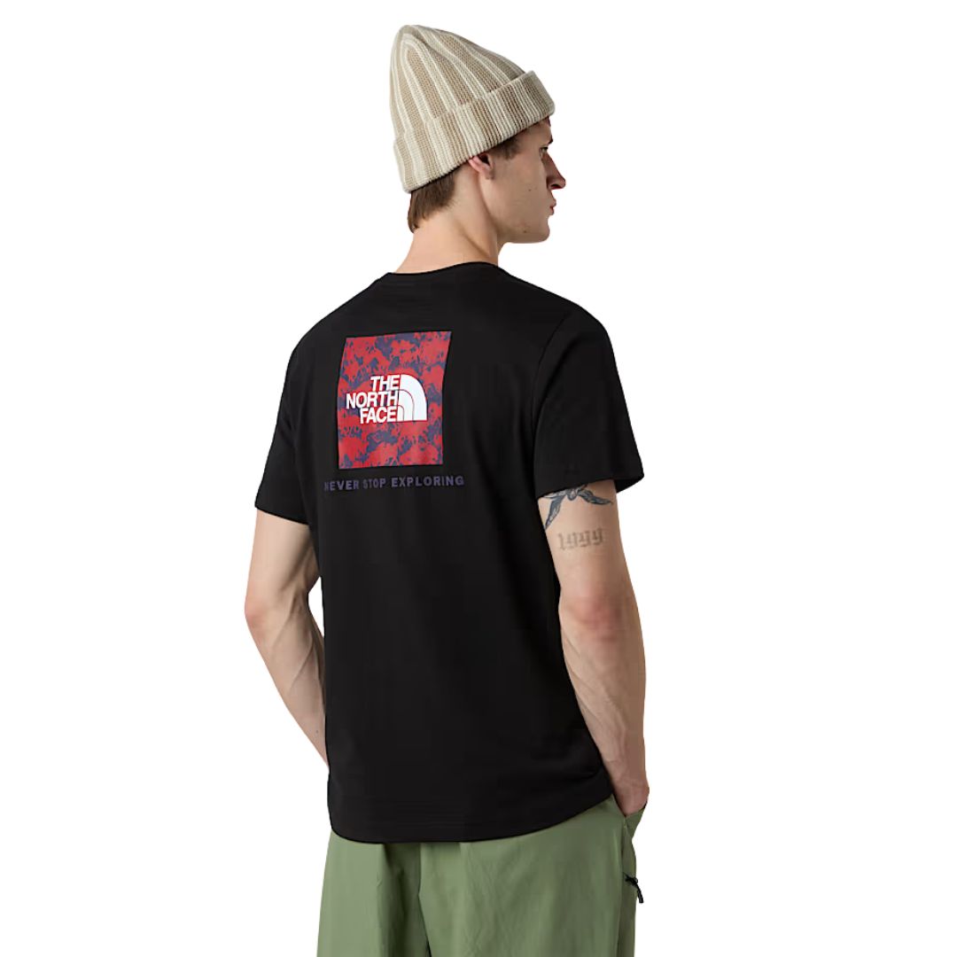 Modelo de perfil mostrando la parte trasera de la camiseta The North Face NSE Box Raku Horse Infill color TNF Black con estampado rojo.