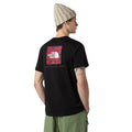 Modelo de perfil mostrando la parte trasera de la camiseta The North Face NSE Box Raku Horse Infill color TNF Black con estampado rojo.