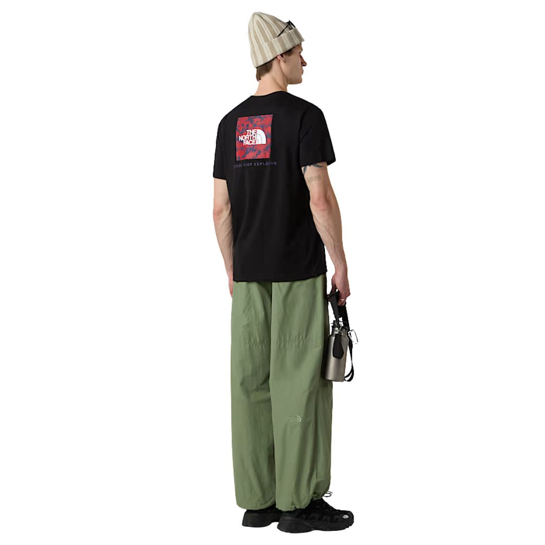 Modelo de espaldas vistiendo camiseta The North Face NSE Box Raku Horse Infill negra con estampado rojo en la espalda.