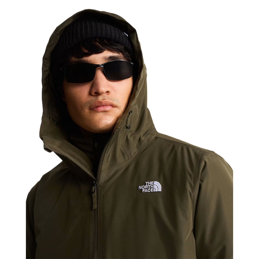 Retrato de modelo con la capucha puesta de la chaqueta The North Face Carto Mono Triclimate en New Taupe Green, con logotipo bordado visible en el pecho izquierdo.