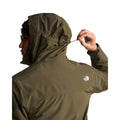 Modelo ajustando el cordón de la capucha de la chaqueta The North Face Carto Mono Triclimate en New Taupe Green, con logotipo bordado en el hombro trasero.