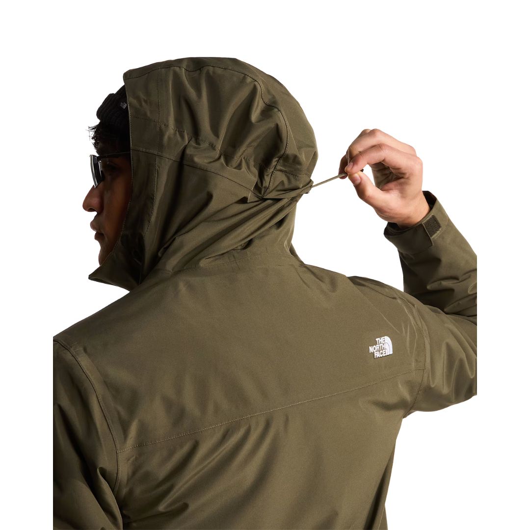 Modelo ajustando el cordón de la capucha de la chaqueta The North Face Carto Mono Triclimate en New Taupe Green, con logotipo bordado en el hombro trasero.