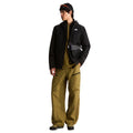 Look completo con la chaqueta The North Face Carto Mono Triclimate negra abierta, bolso bandolera con mosquetón, camiseta y pantalón técnico, vista de cuerpo entero.