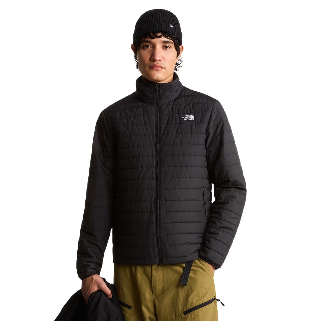 Modelo con la chaqueta interior acolchada de The North Face Carto Mono Triclimate negra puesta y la chaqueta exterior en la mano, con cuello alto y bolsillos con cremallera.